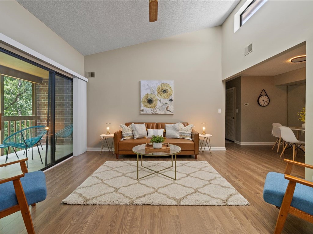 Professionally photographed living room with a brown sofa, blue chairs and vaulted ceiling