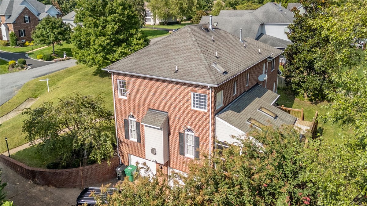 Closer aerial view of the brick home and its outdoor spaces